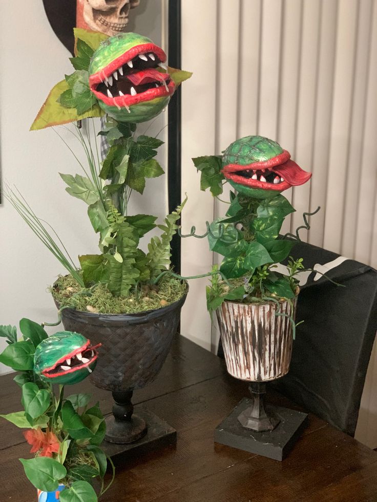 two plants with fake teeth on them sitting on a table next to a skull head