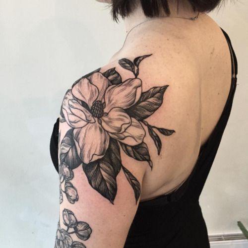 a woman wearing a black dress has a flower tattoo on her left arm and shoulder