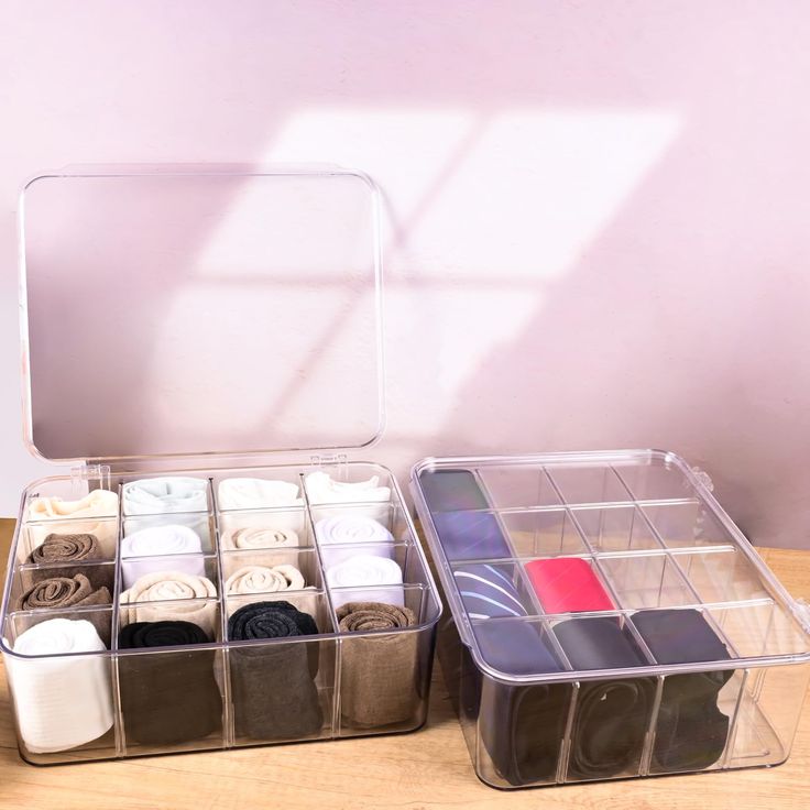 two clear storage containers filled with different types of fabric and scissors on a wooden table