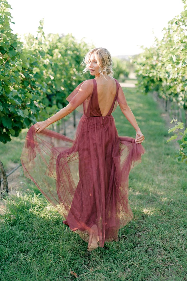 a woman standing in the middle of a vineyard