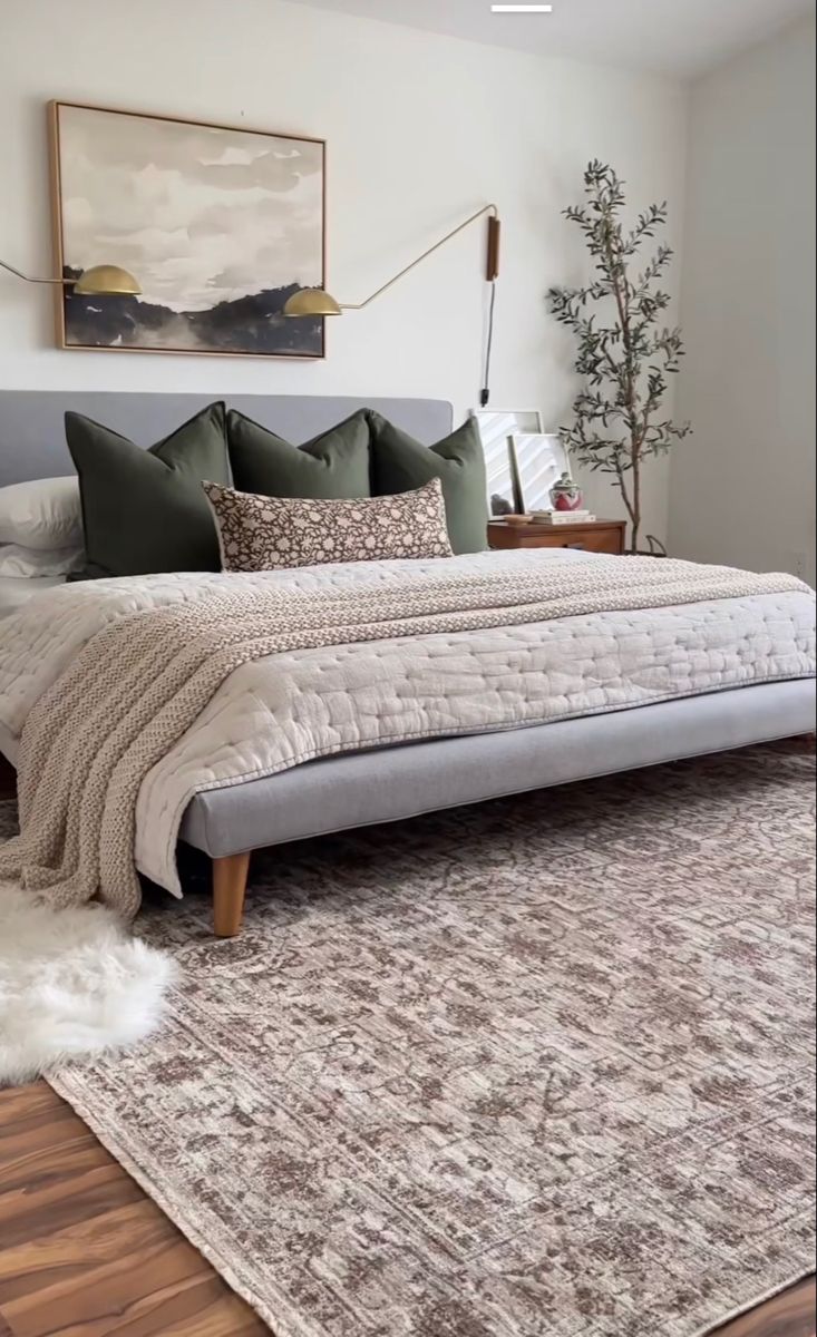 a large bed sitting on top of a wooden floor next to a white wall and window