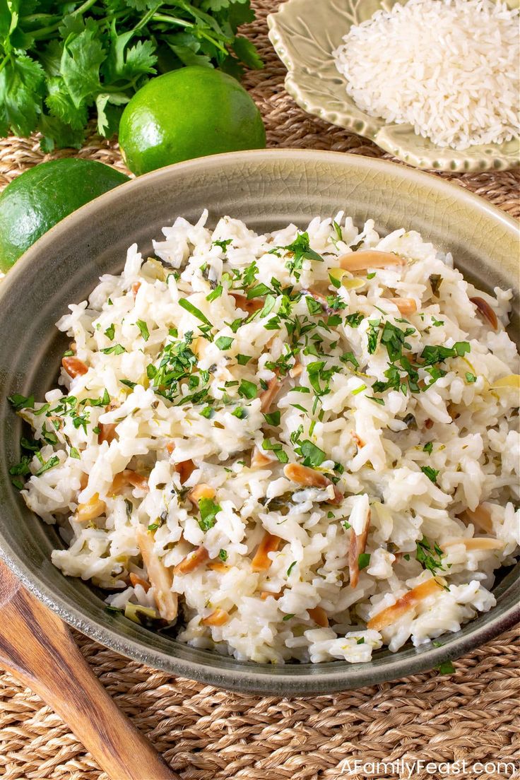 a bowl filled with rice and garnished with parsley next to limes