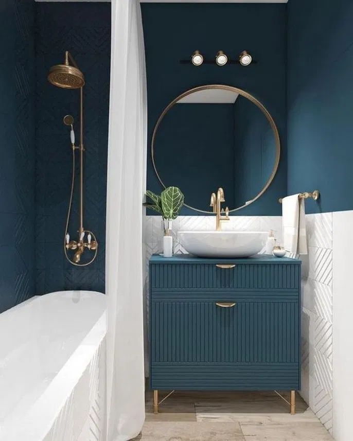 a bathroom with blue walls and gold fixtures on the vanity, along with a white bathtub