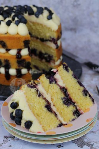 a cake with blueberries and white frosting is on a plate next to another cake