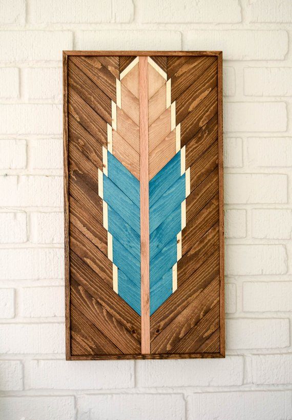 a wooden wall hanging on the side of a white brick building with a blue arrow painted on it