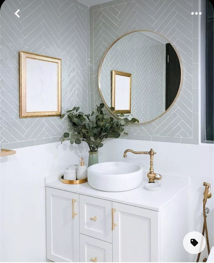 a white sink sitting under a mirror next to a wall mounted faucet in a bathroom