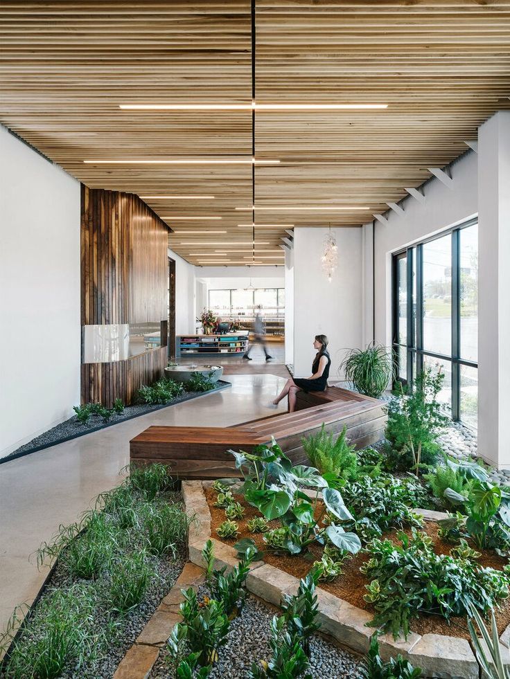 a woman sitting on a bench in the middle of a room with lots of plants