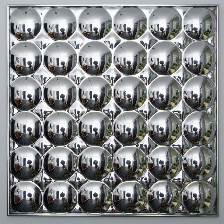 the reflection of buildings in mirrors is shown on a metal wall paneled with silver balls