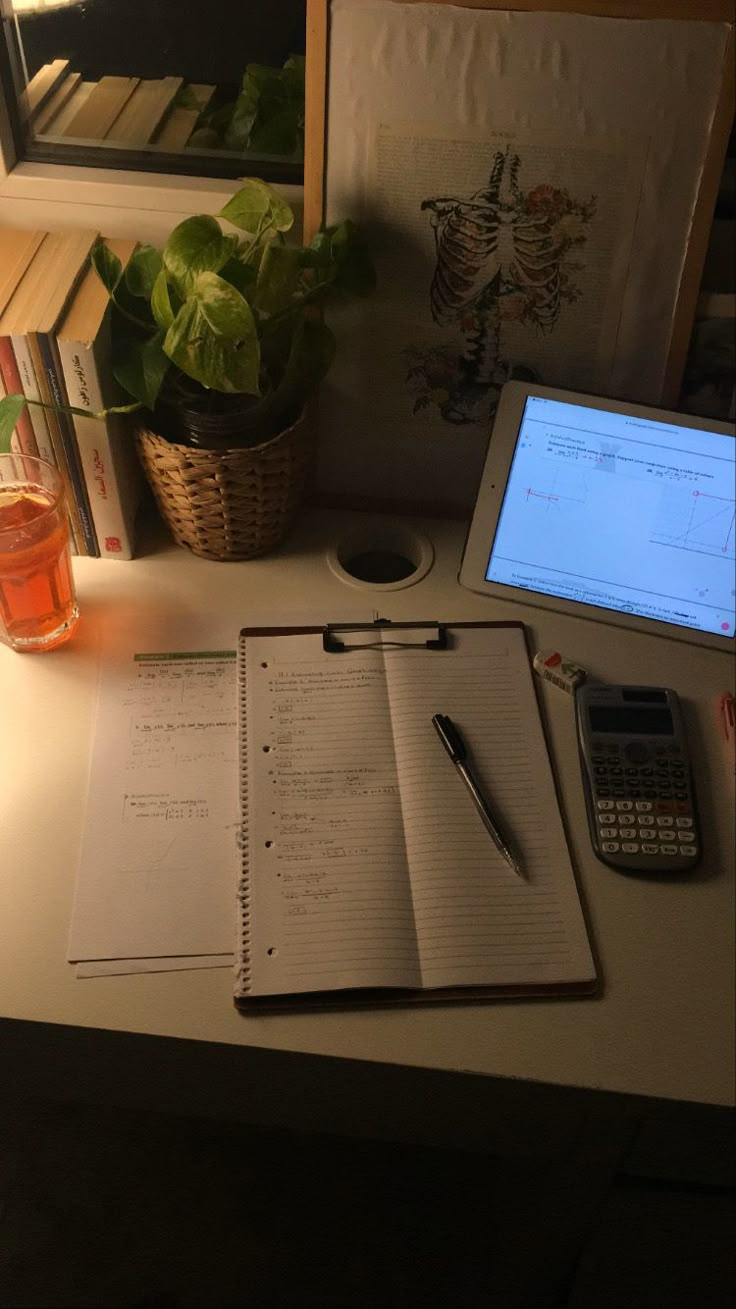 an open notebook sitting on top of a desk next to a laptop computer and calculator