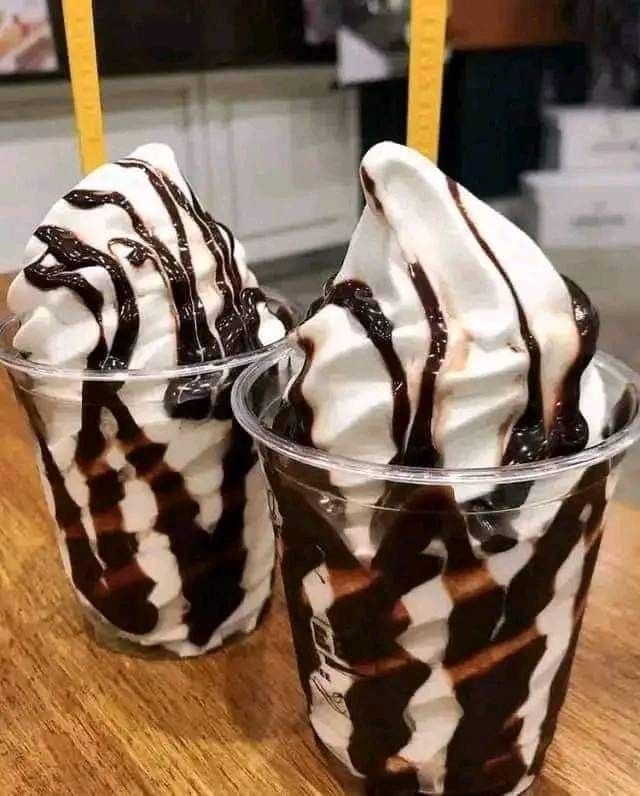 two ice cream sundaes sitting on top of a wooden table next to each other