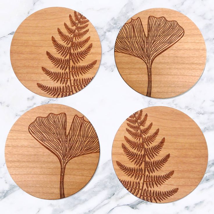 four wooden coasters with leaves on them