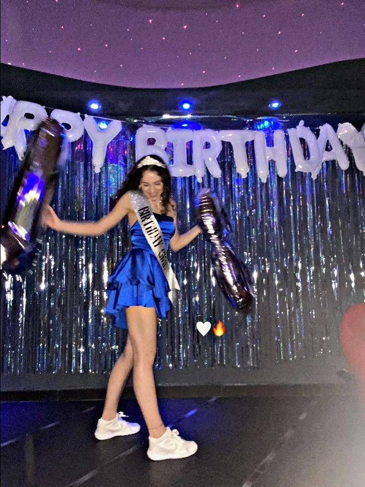 a woman in a blue dress is holding two trophies