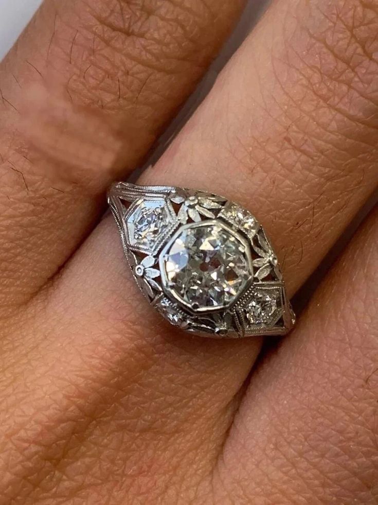 a woman's engagement ring with an old cut diamond in the center, on her finger