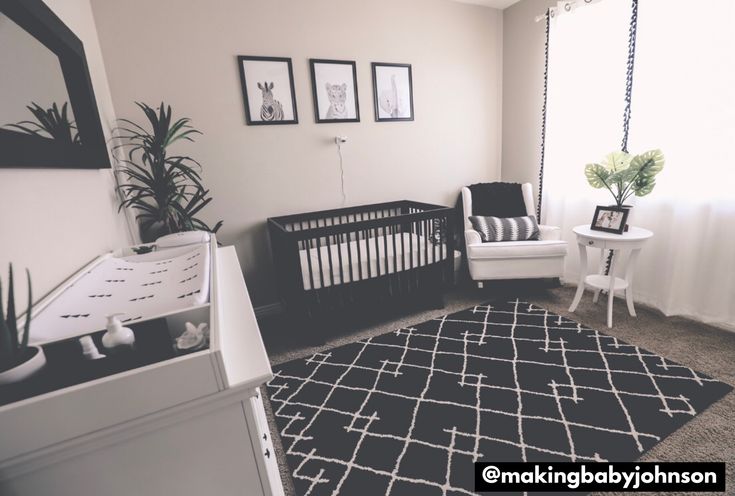 a baby's room with a black and white rug, chair, crib, table and pictures on the wall