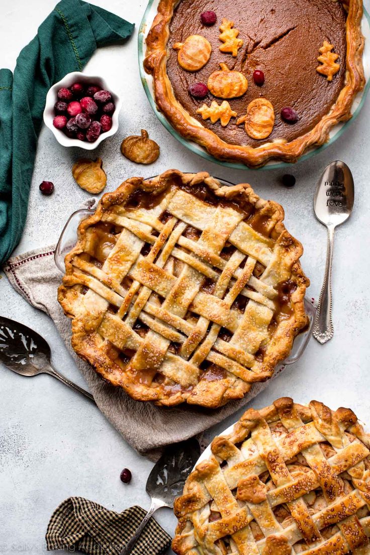 two pies sitting next to each other on top of a white table with spoons