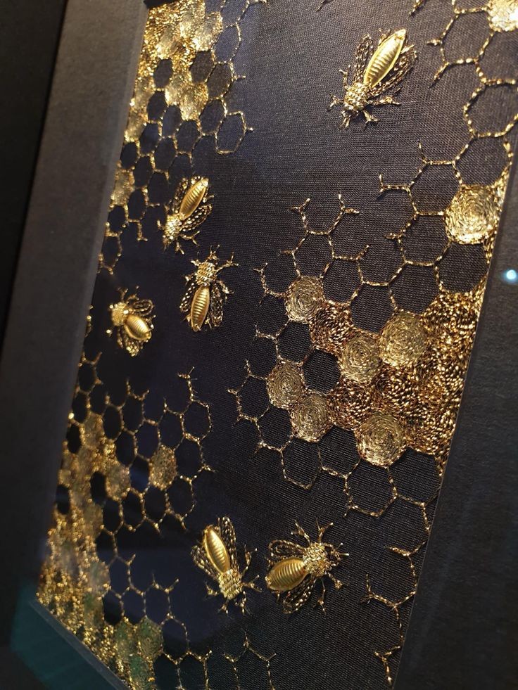 gold bees and honeycombs are on the black fabric in front of a window