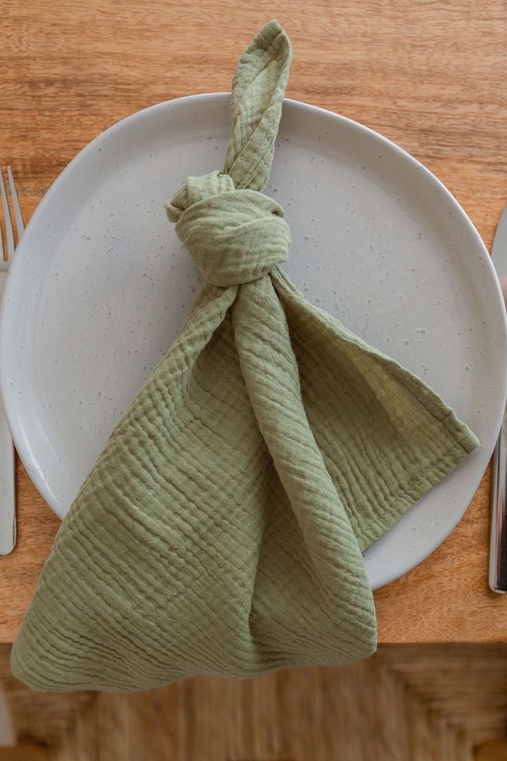 a plate with a napkin tied around it on top of a table next to a fork and knife