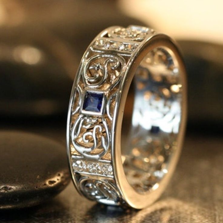 an intricately designed wedding ring sits on a table