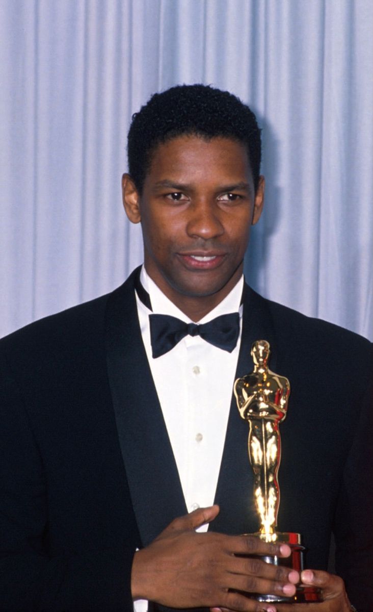 a man in a tuxedo holding an award for his role in the oscars