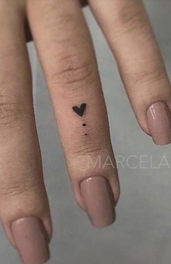 a small heart tattoo on the middle finger