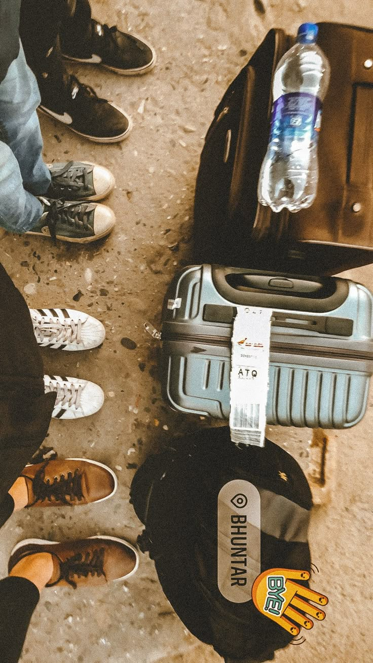 several people standing around with their luggage and water bottles on the ground in front of them