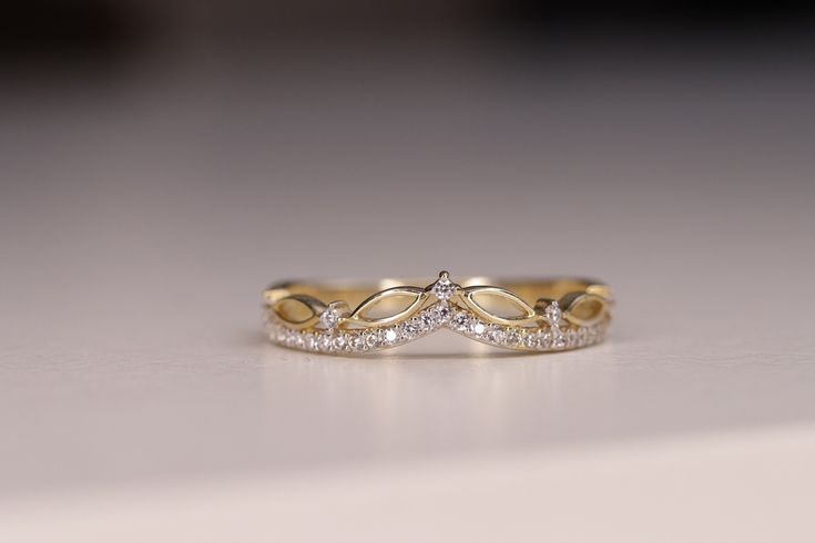 two gold wedding bands with diamonds on them sitting on top of a white countertop