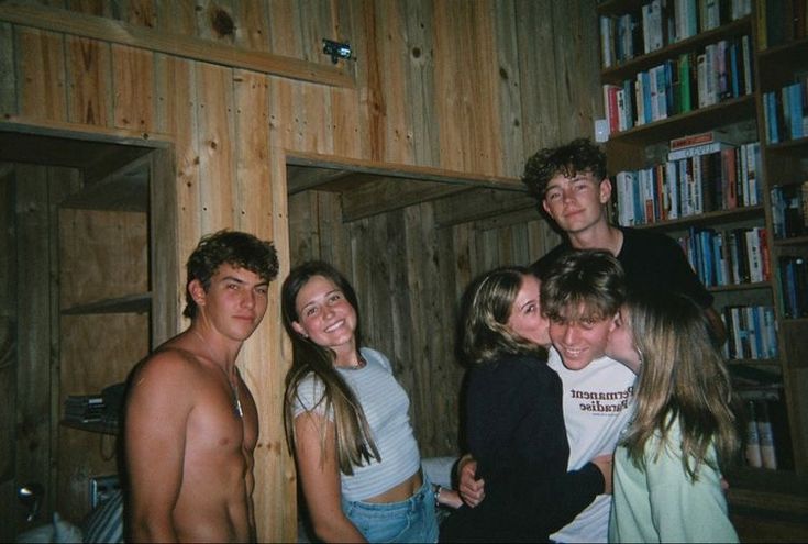 a group of people standing next to each other in front of a bookshelf