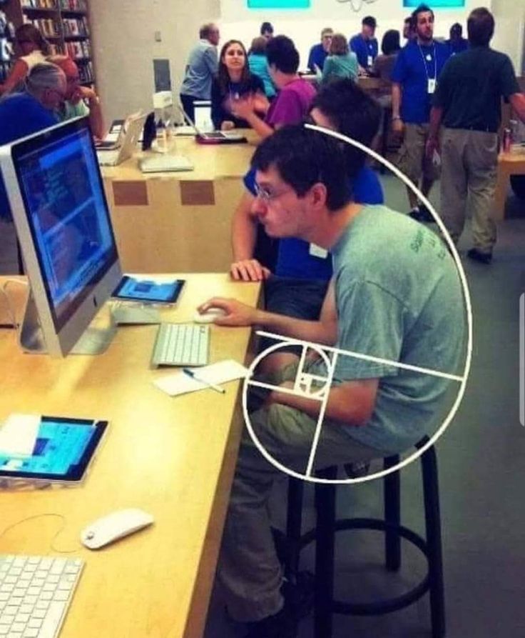 a man sitting in front of a computer on top of a desk next to another person