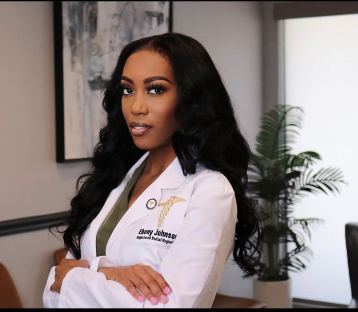 a woman in a white lab coat is posing for the camera with her arms crossed