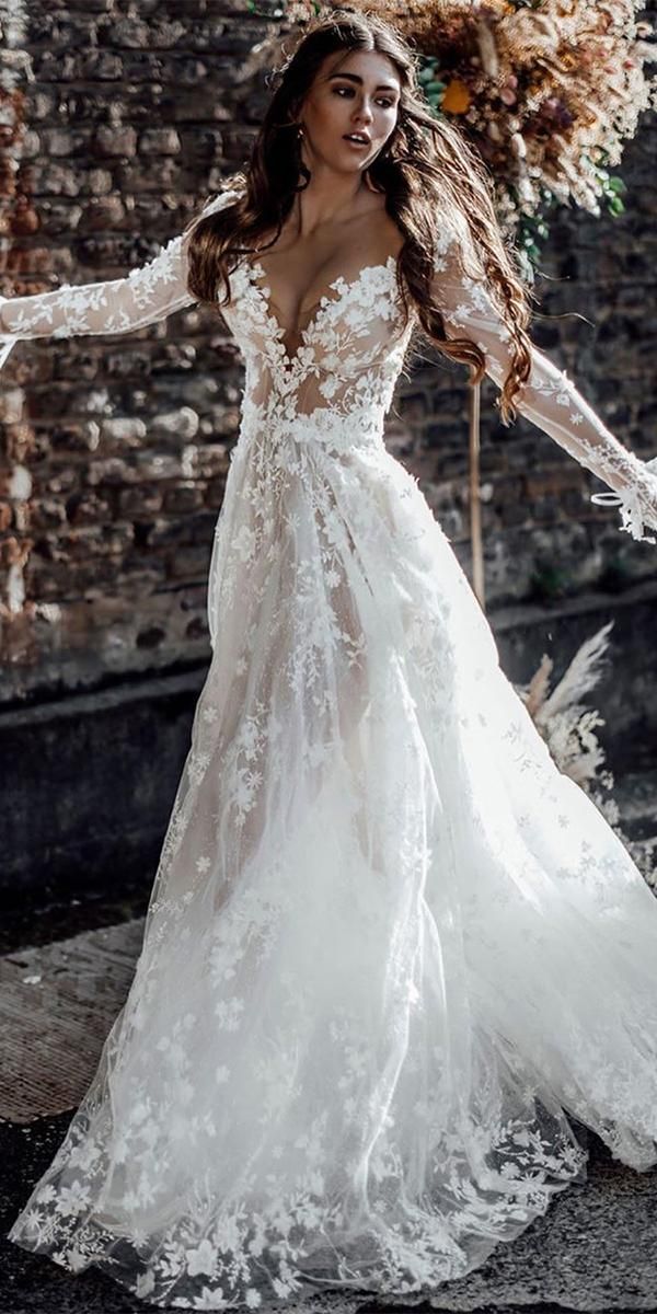 a woman in a wedding dress with long sleeves and flowers on her head is posing for the camera