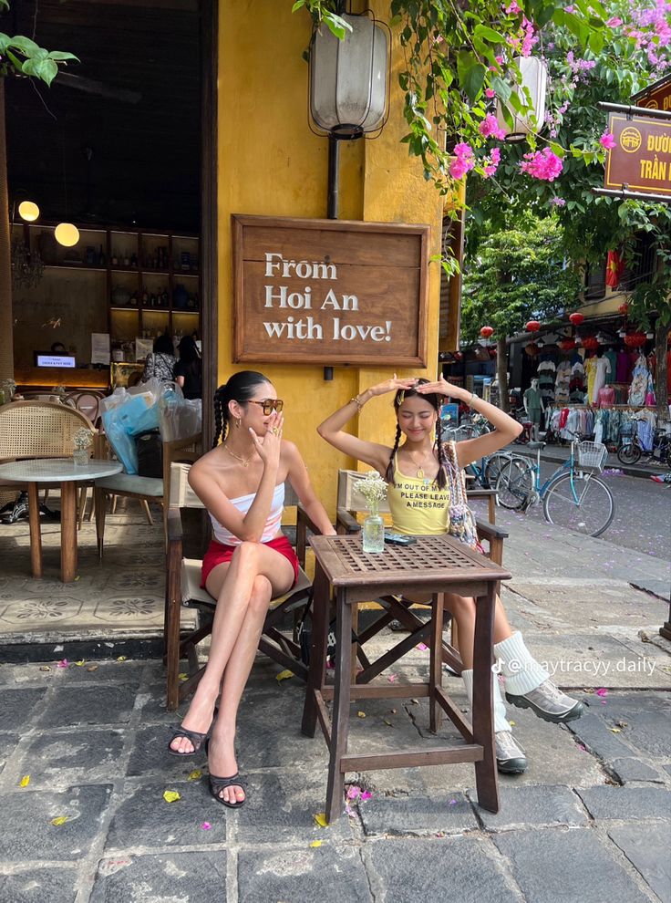 two women sitting at a table in front of a store