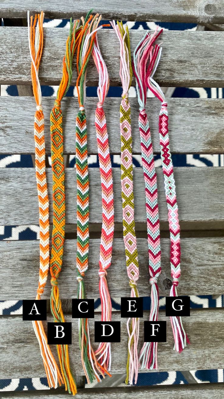 several different colors of braids are hanging on a wooden wall with the words abcdef