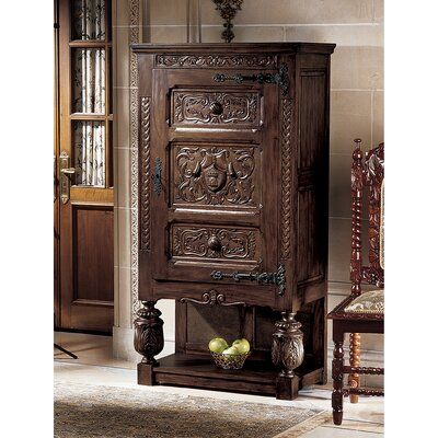 a wooden cabinet with carvings on the doors and drawers, in a room that has a chair next to it