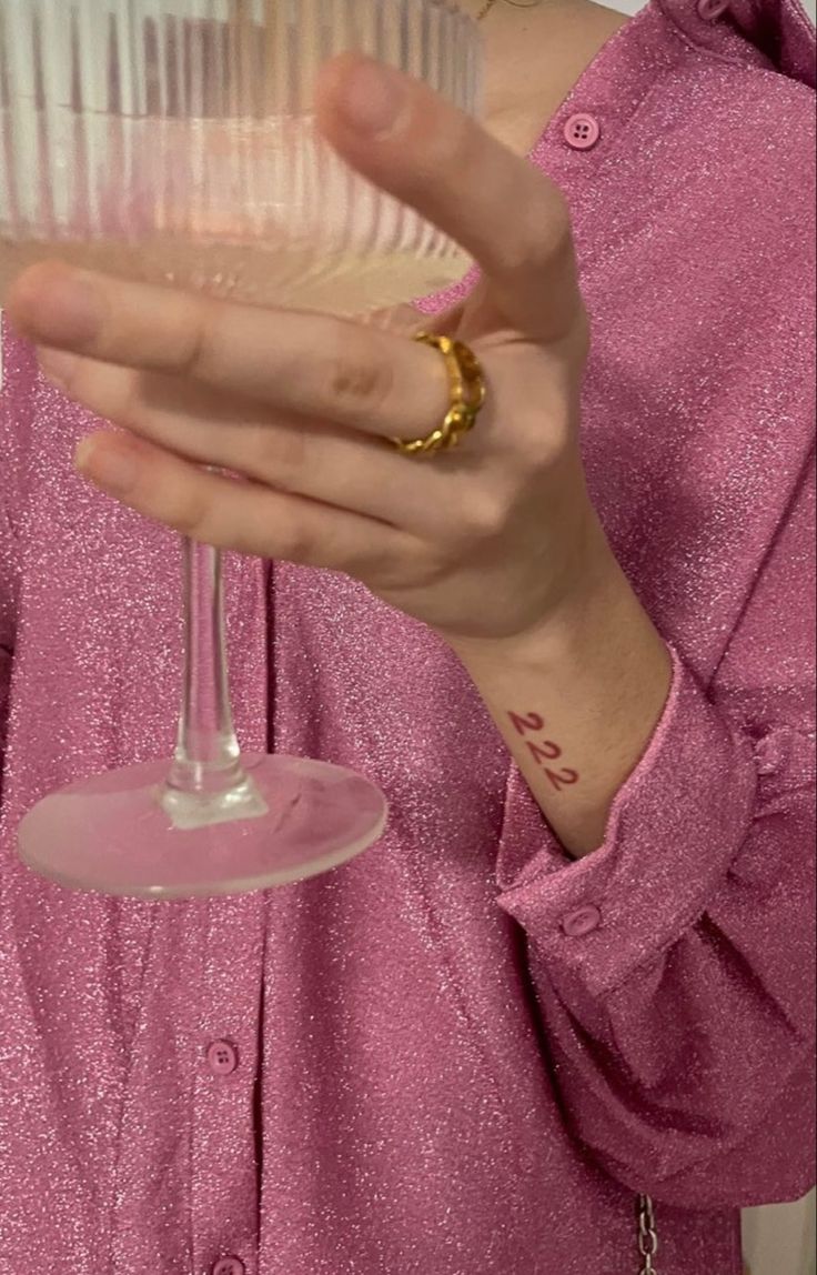 a woman in a pink shirt holding a wine glass with the word love written on it