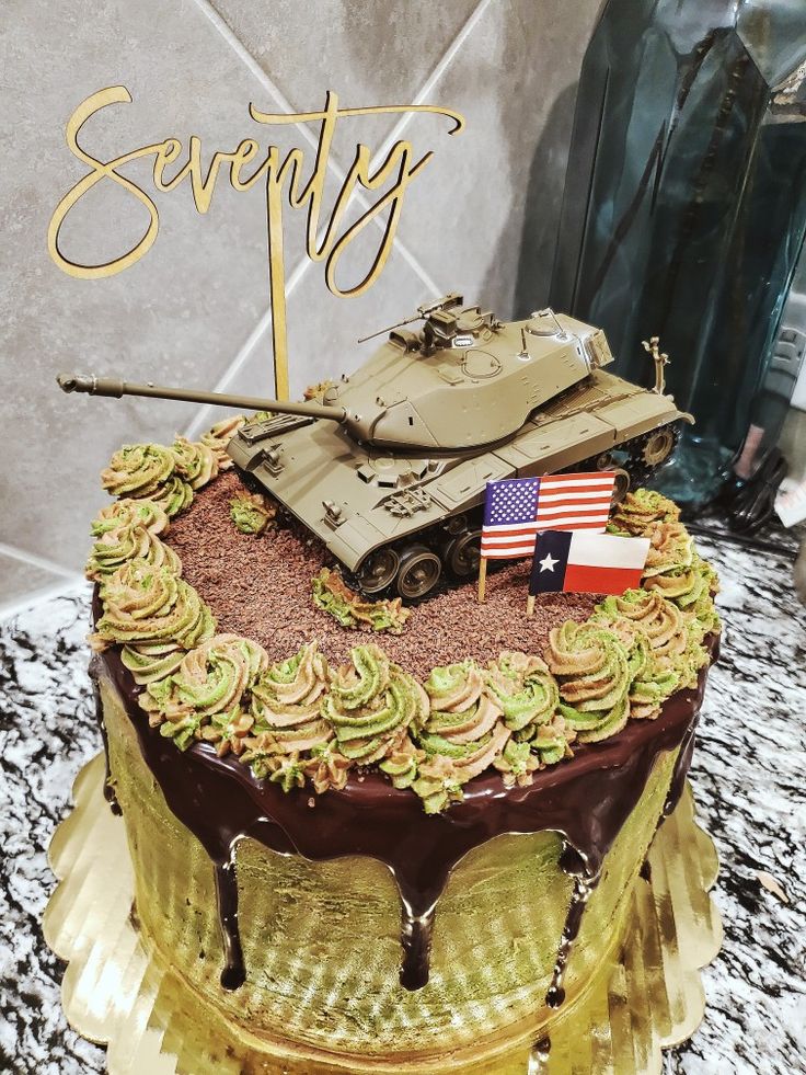 a birthday cake with a tank on top and the word seventy written in gold lettering