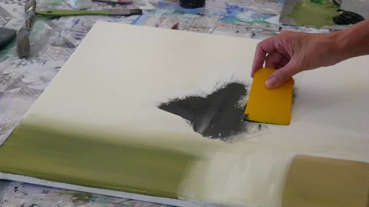 a person is painting on a canvas with yellow and gray paint