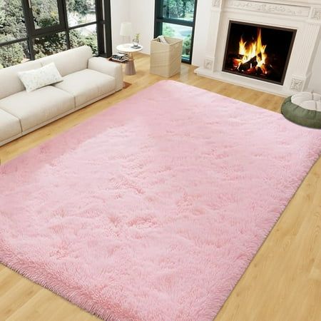 a living room with white furniture and a pink rug in front of a fire place