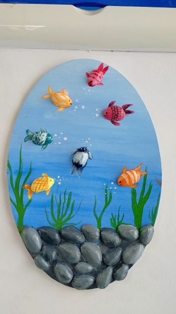 a painting on the side of a wall with fish swimming in water and rocks under it