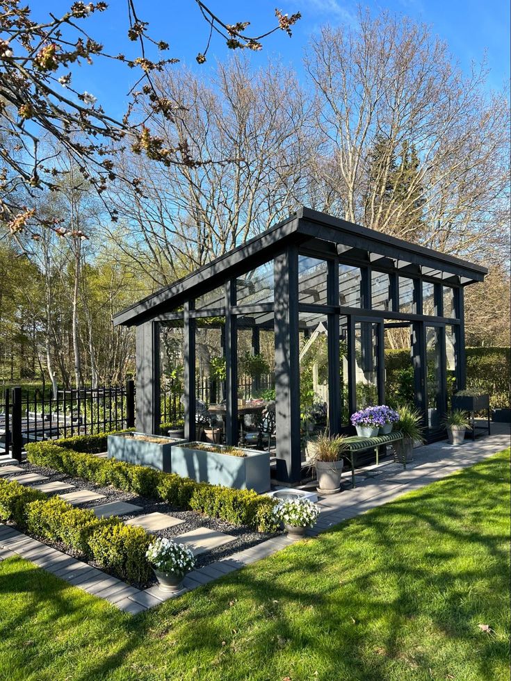 a small glass house sitting in the middle of a lush green park