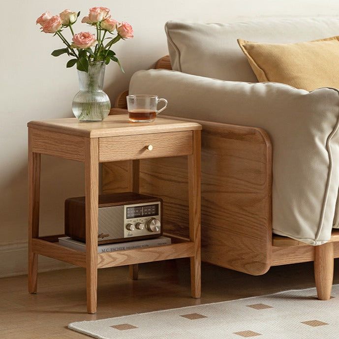 a wooden table with a radio on it next to a couch and flowers in a vase