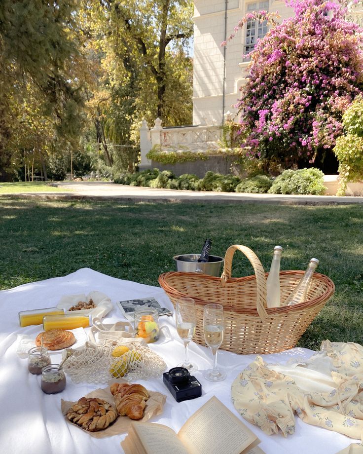 a picnic table with food and wine on it in front of a large white building