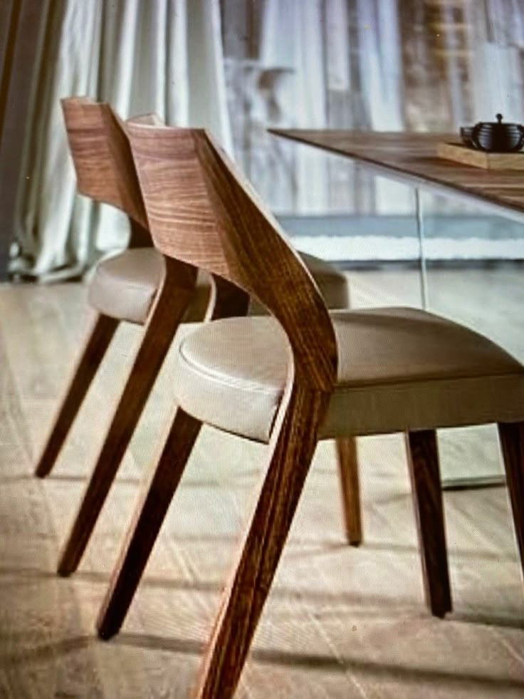 two chairs sitting next to each other in front of a wooden table with cups on it