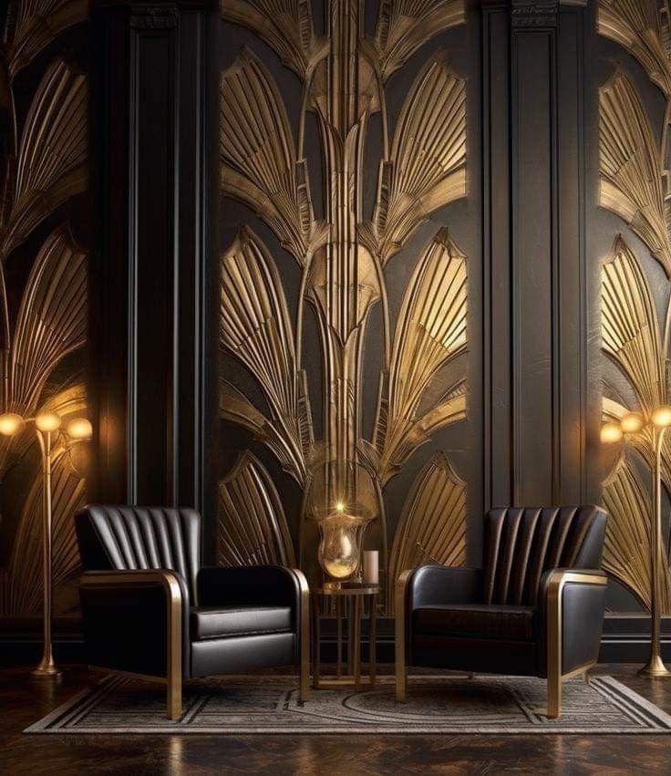 two chairs and a table in front of a wall with gold art deco leaves on it