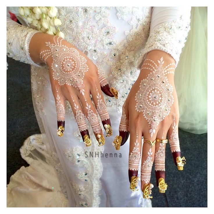 two hands with gold and white designs on them, one is holding a bouquet of flowers