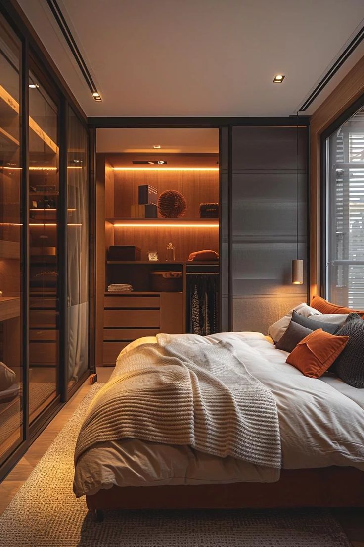 a bedroom with a large bed next to a walk in closet that also has glass doors