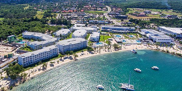 an aerial view of the resort and beach area with boats in the water, surrounded by lush green trees