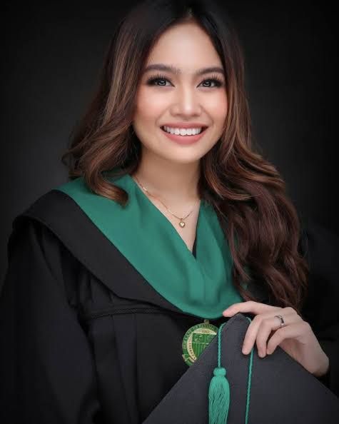 a woman wearing a graduation gown and holding a green tassel