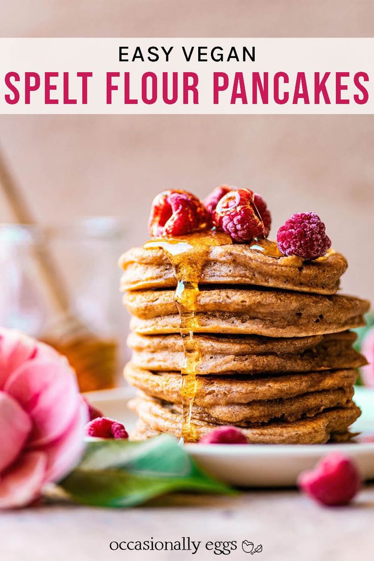 a stack of pancakes with raspberries on top and syrup being drizzled over them