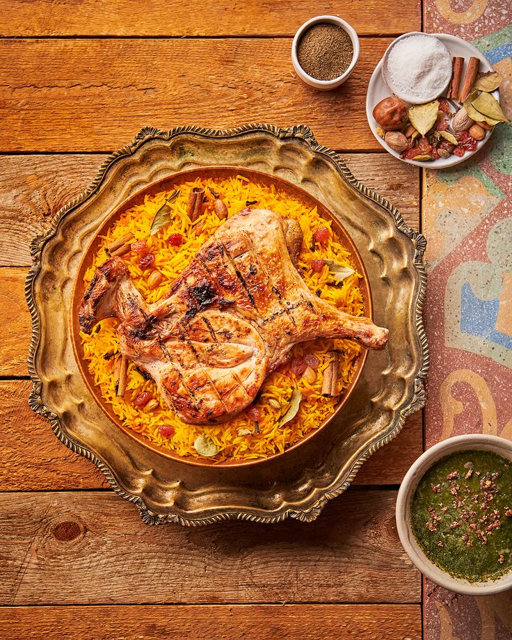 an overhead view of a plate of food on a wooden table with bowls of spices and seasonings