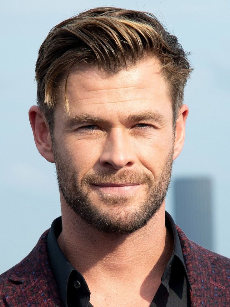 a close up of a person wearing a suit and tie with a sky in the background